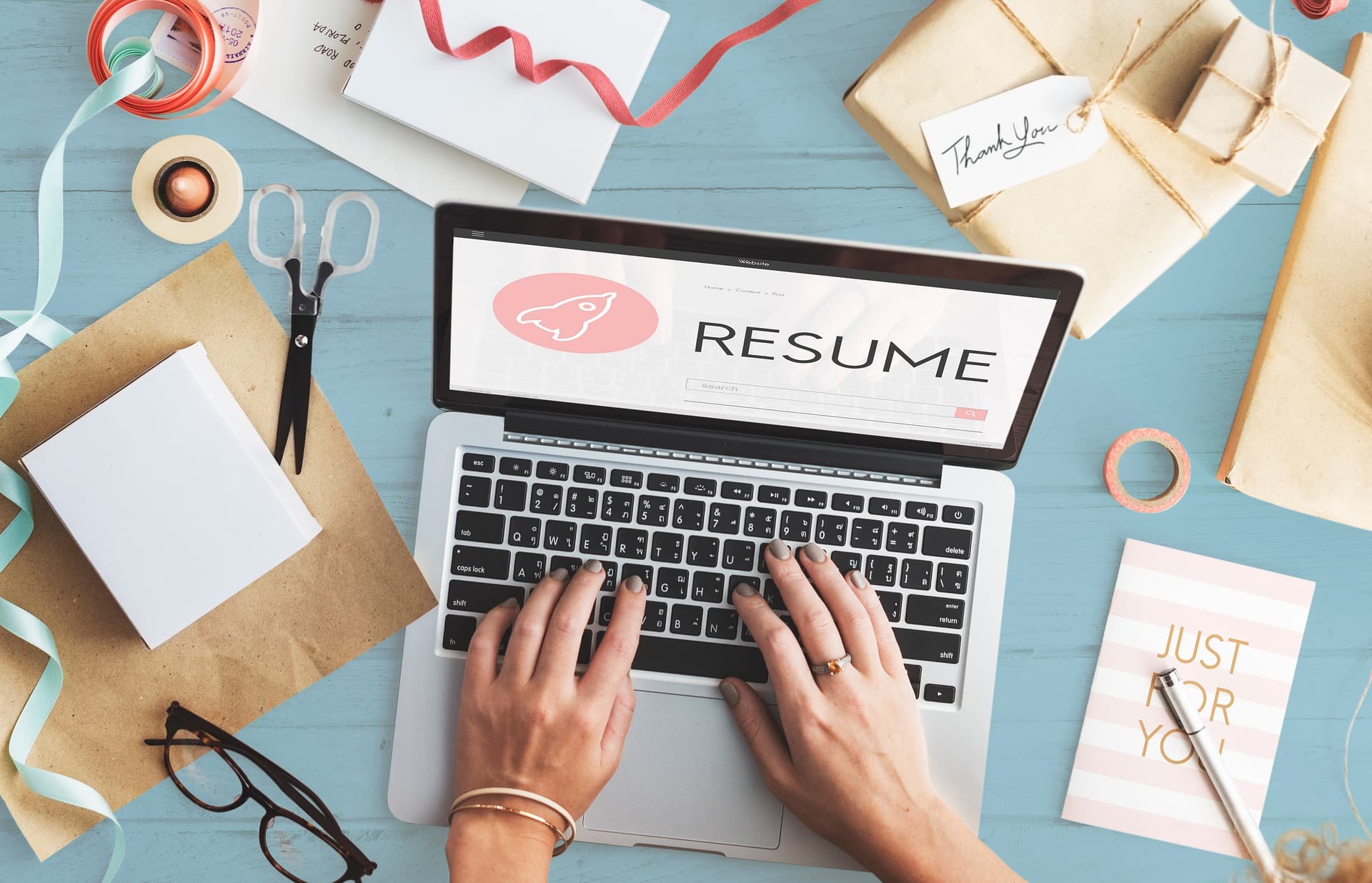 Job seeker writing computer skills on a resume using a laptop