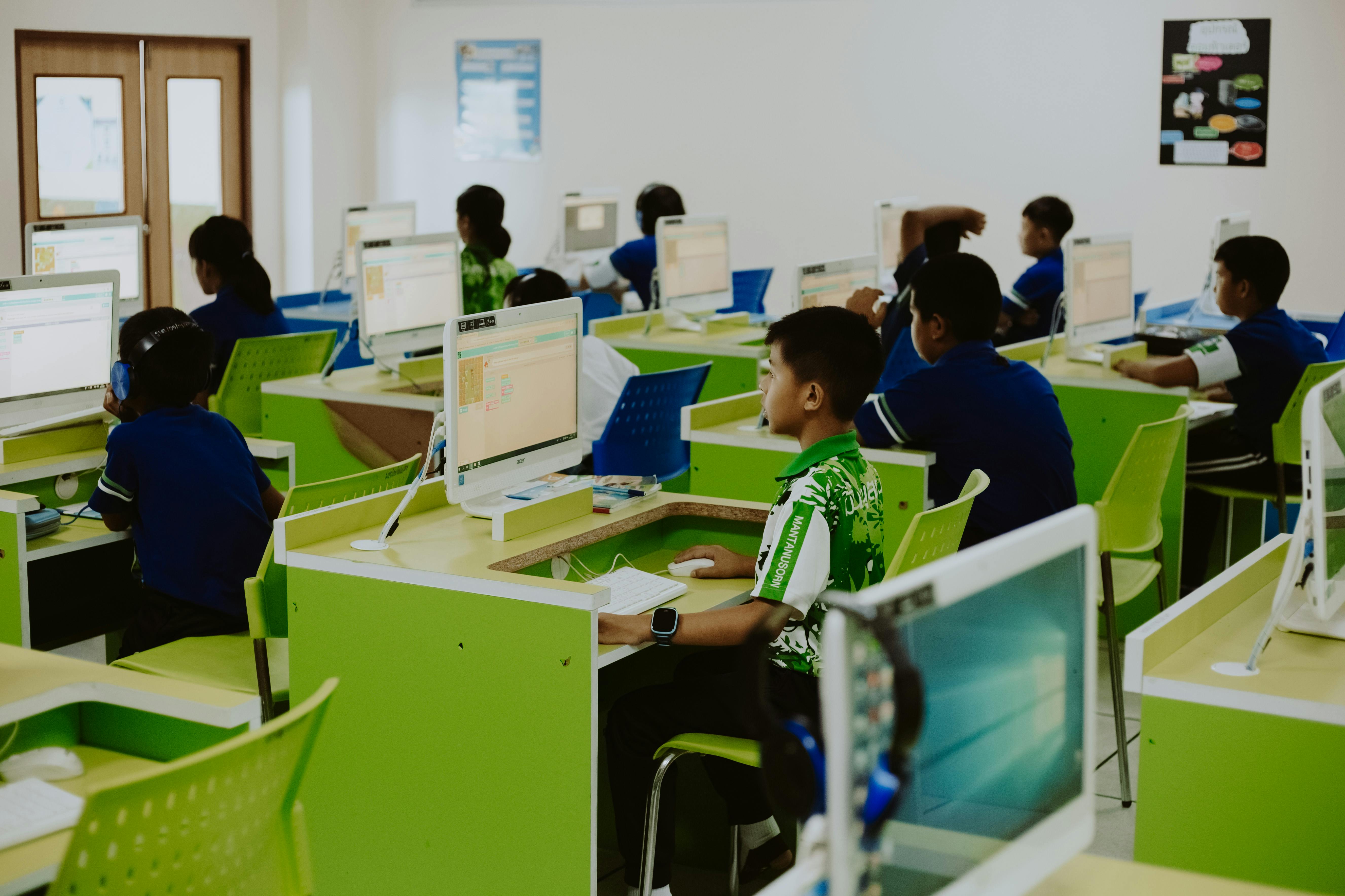 Teacher using laptop in classroom with digital board